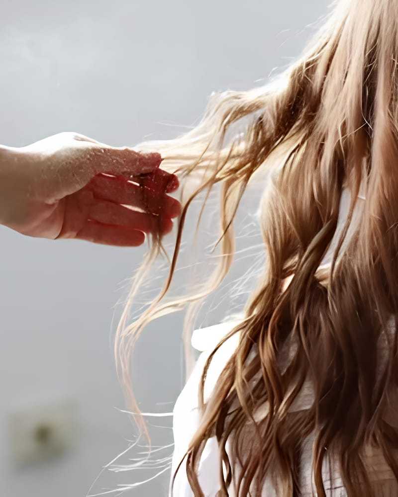 Hand touching flowing blonde hair, capturing a serene and gentle interaction.