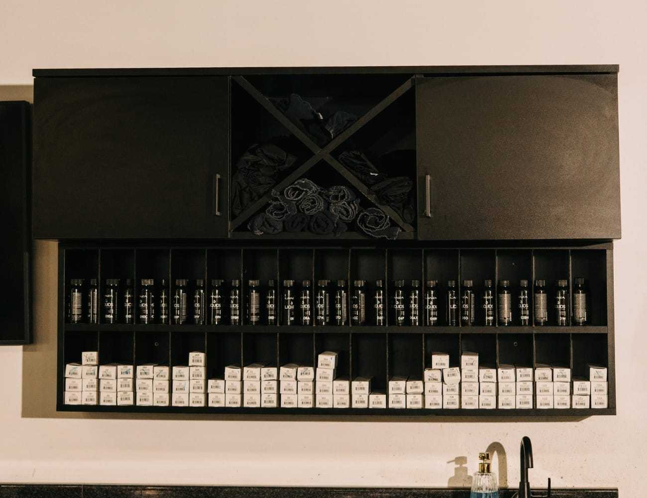 Wall-mounted cabinet with rows of hair products and towels neatly arranged.