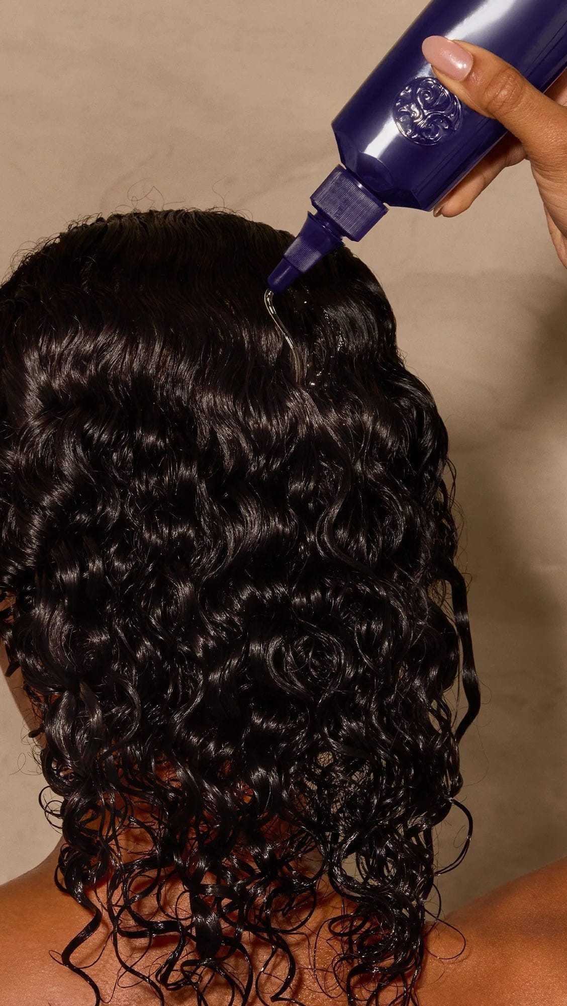 Applying hair product to enhance curly hair texture.