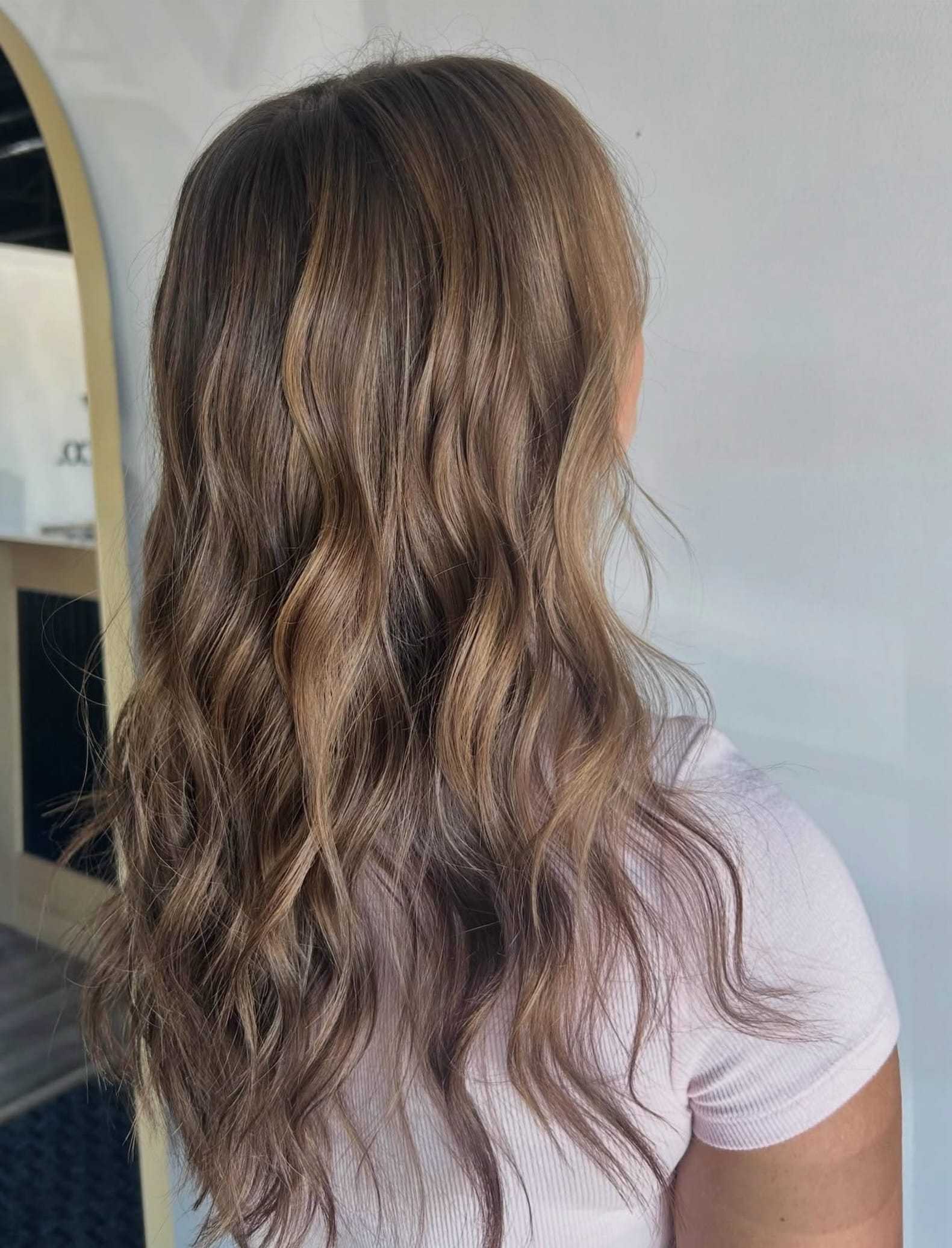 Wavy brown hair cascading on a woman's back, showcasing a salon style.