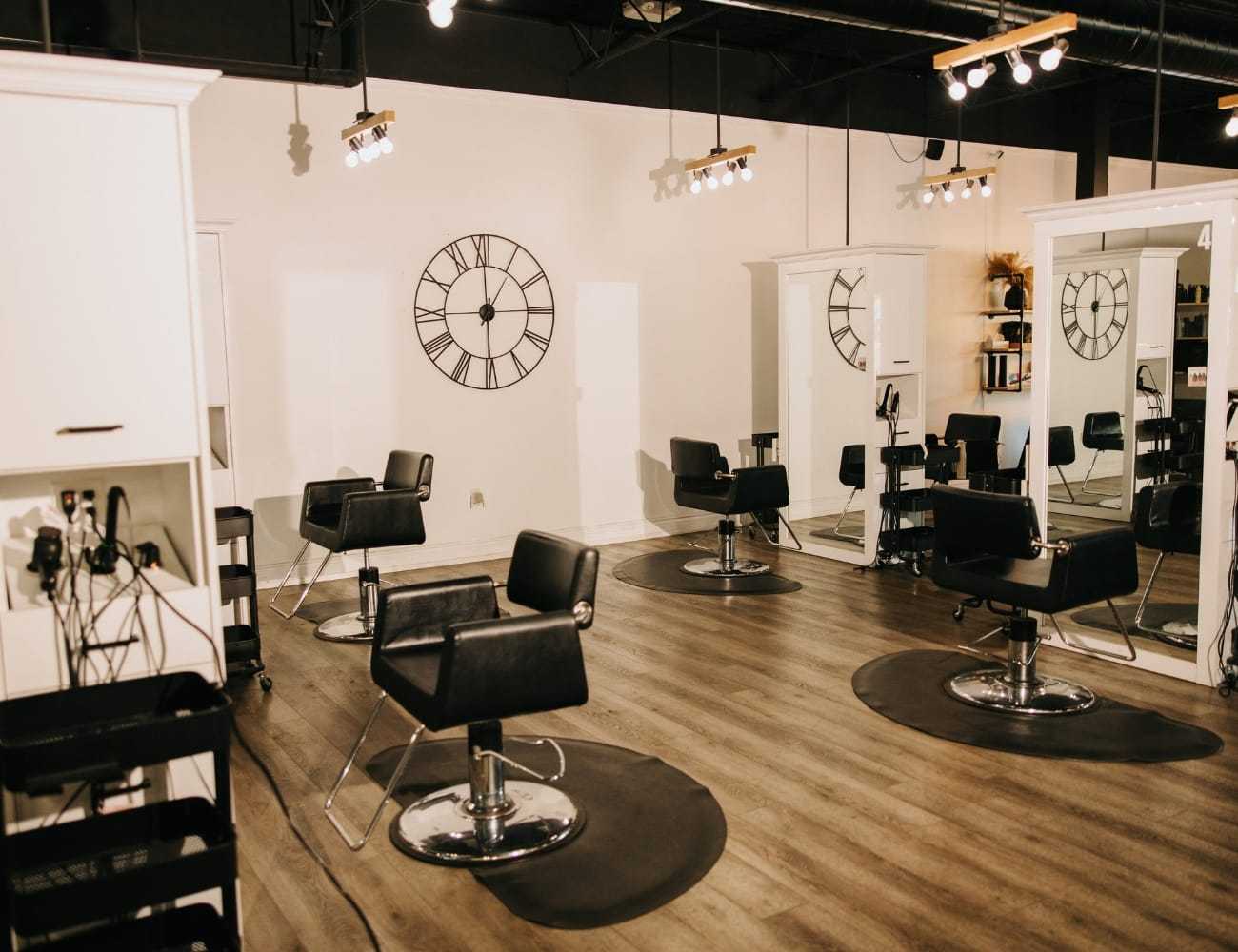 Modern hair salon with black chairs, large mirrors, and stylish decor.