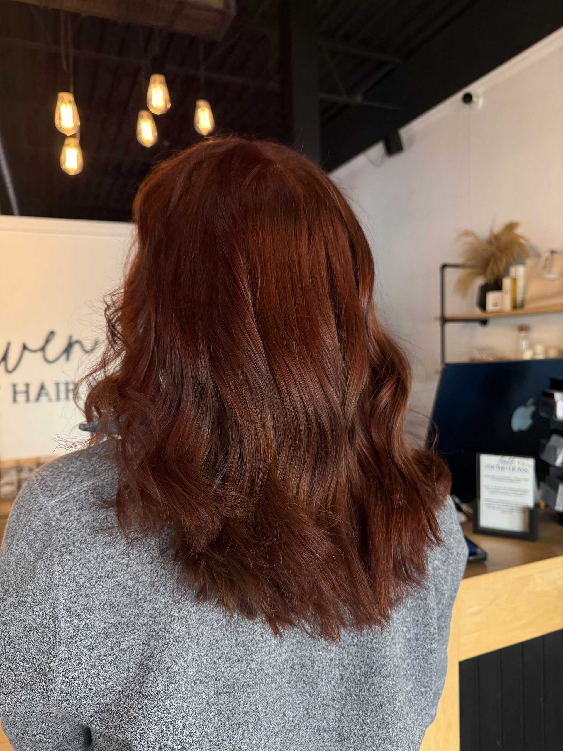 Brown-haired person in a salon with warm lighting and a modern interior.