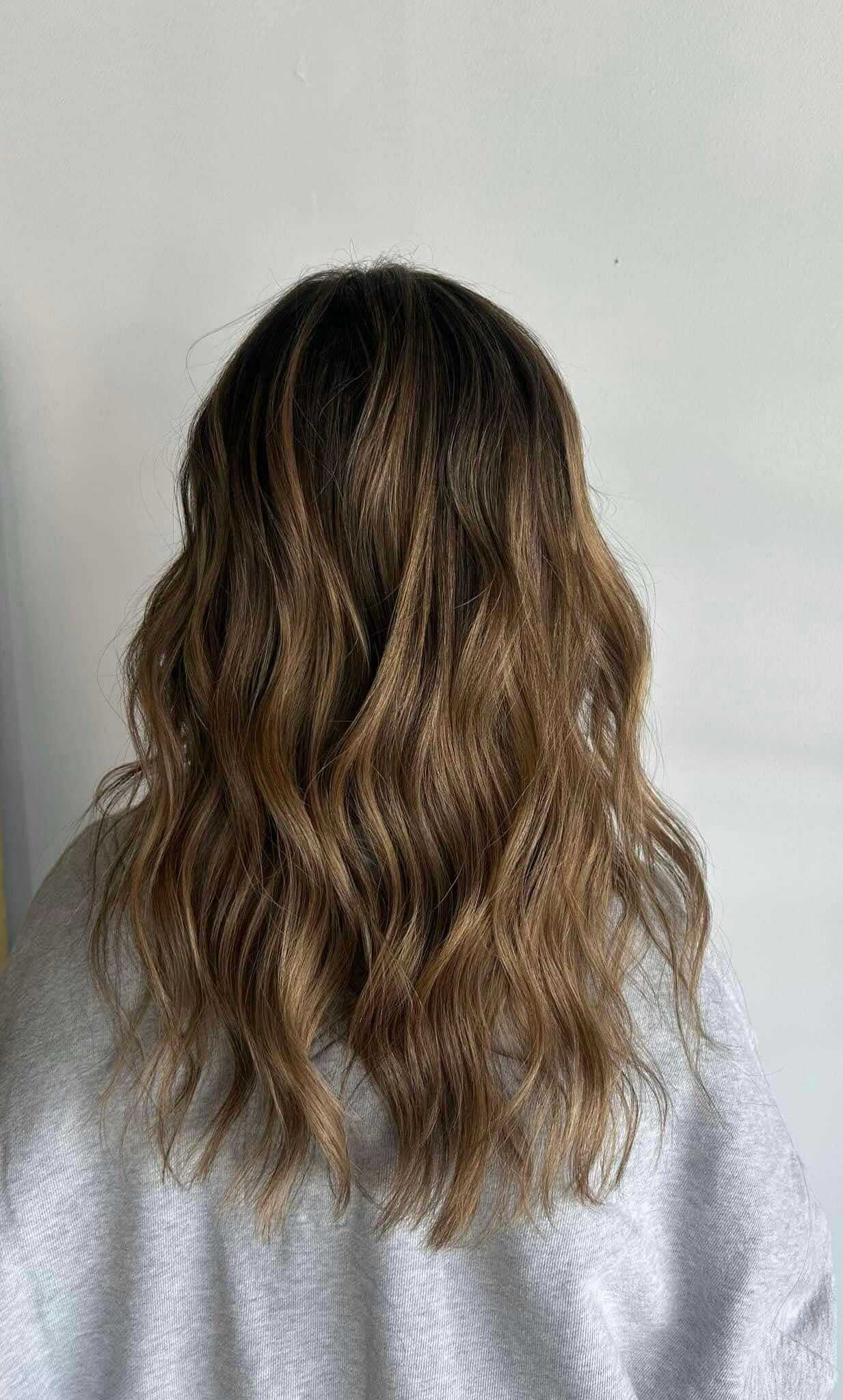 Wavy brown hair from the back, wearing a gray shirt against a plain background.