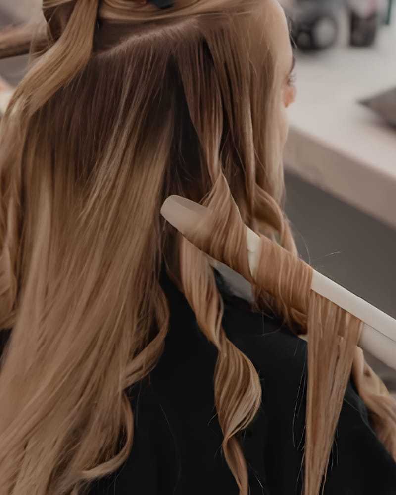 Hair being styled with a curling iron in a salon.